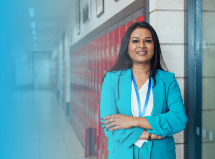 An educator standing in front of lockers in a school hallway